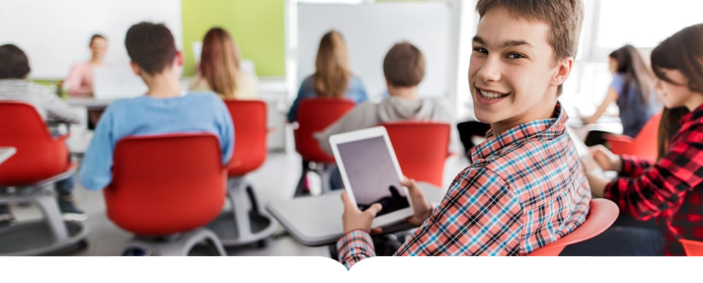 Boy in school holding a tablet and smiling