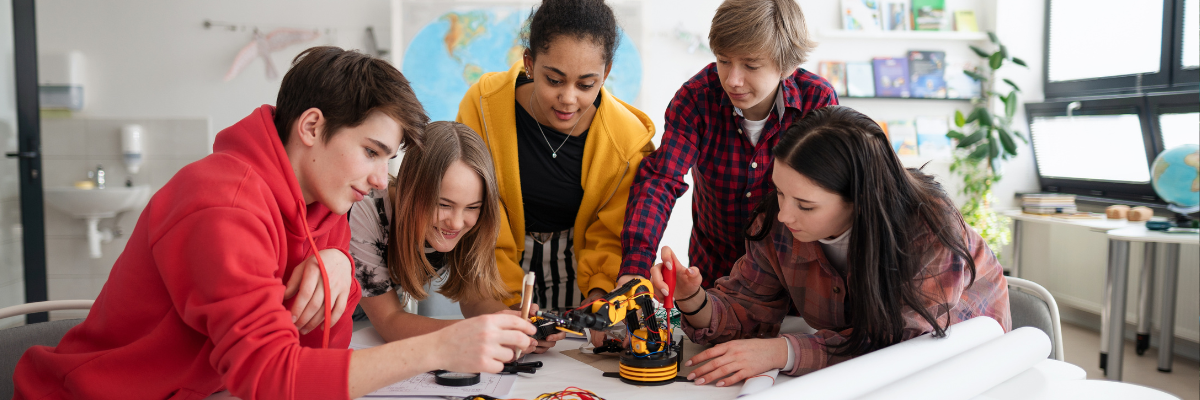 Kids sitting around a table building a robot