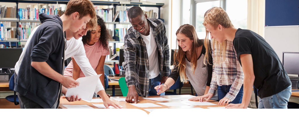 Students standing around a table looking at papers