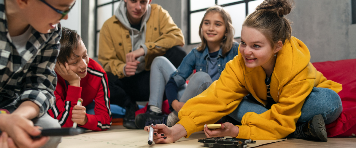 Students sitting on floor drawing on paper